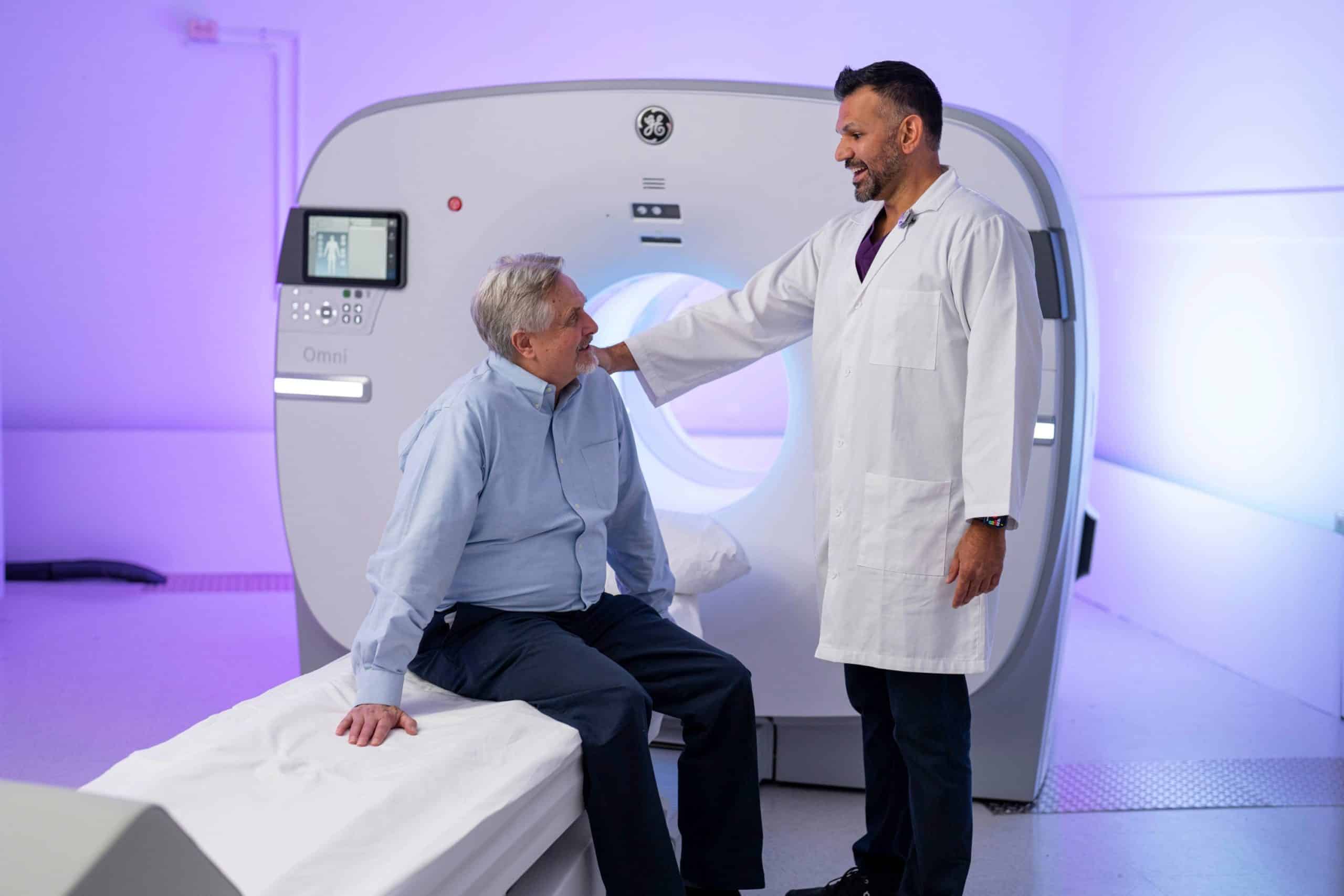 Doctor talking to patient sitting on Omni Legend PET/CT scanner